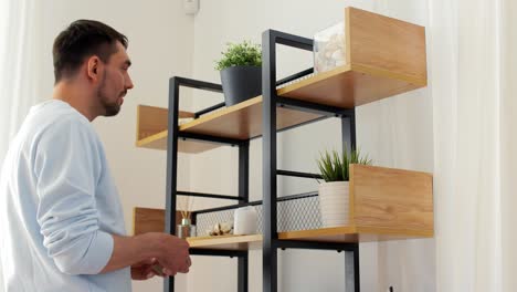 Man-with-Matchsticks-Lighting-Candles-at-Home.home-improvement,-decoration-and-people-concept--man-with-matchsticks-lighting-candles-on-shelf